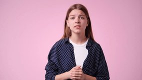 4k video of girl who puts her hands to her chest on pink background.