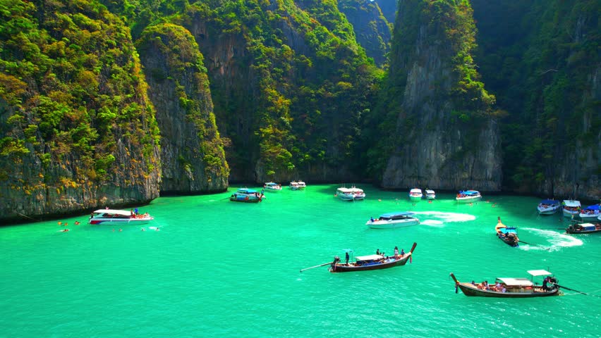 Aerial views from drones flying over tropical seas, Limestone mountains and clear blue waters, tour boats and long-tail boat. Phi Phi Islands, Krabi, most beautiful places to visit in Thailand. 4K UHD