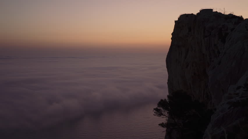 A scenic aerial view of clouds over a tranquil sea during a beautiful sunset captured from a cliff | Shutterstock HD Video #1100001099