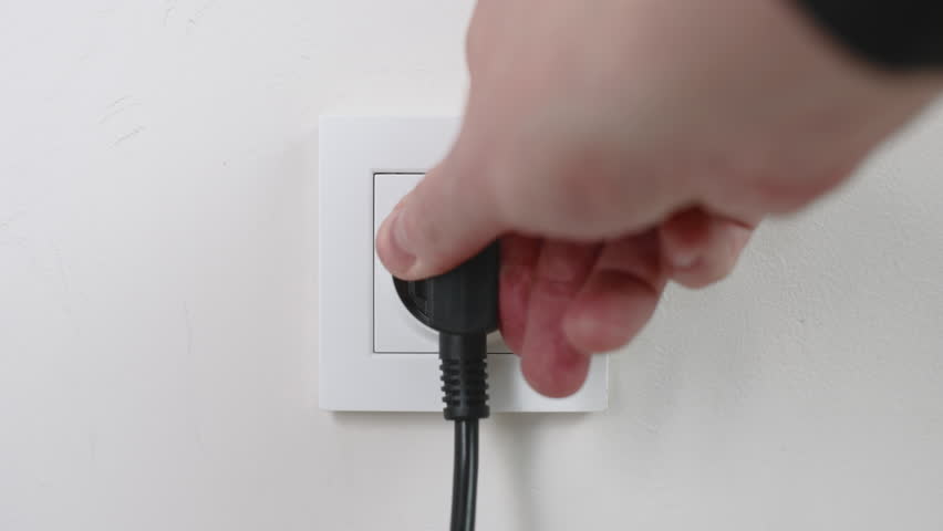 Male hand plugging and unplugging plug into white wall socket. Close-up power socket, caucasian man, charger cable | Shutterstock HD Video #1100001523