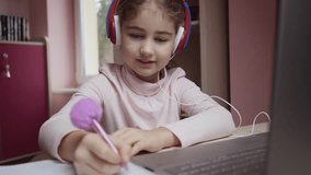 Distance Learning. Schoolgirl Studying Online Using Laptop Making Notes in Copybook. School Student Wearing Headphones Watching Internet Video Course. Caucasian Girl Wear Headphones Learn Online Class - Powered by Shutterstock - Get 15% off with code: PIKWIZARD15