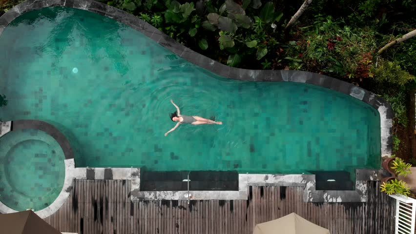 travel woman relaxing in infinity pool enjoying vacation lifestyle at luxury hotel spa with view of tropical jungle, drone view Royalty-Free Stock Footage #1100002775