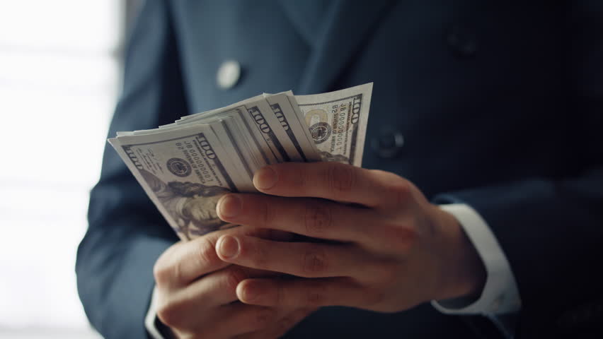 Man hands holding dollar bills close up. Unrecognizable businessman in elegant black suit having pack currency with hundred bucks denomination. Successful investment profit employee salary concept. | Shutterstock HD Video #1100003087