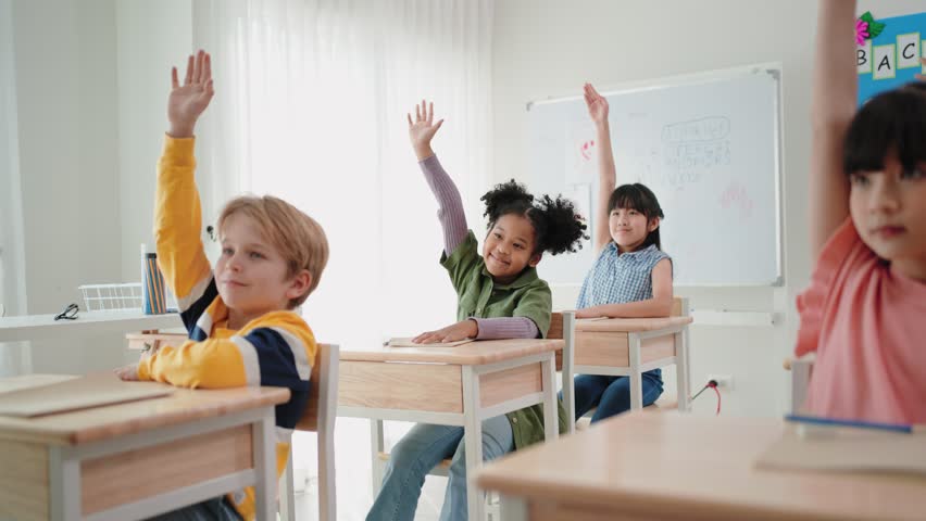Elementary students raising hands to answer question from teacher in the classroom at school | Shutterstock HD Video #1100005563