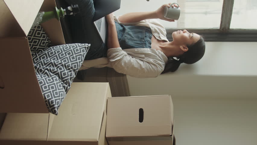 A Female using Laptop in New Home Planning Surrounded by Boxes Royalty-Free Stock Footage #1100005809