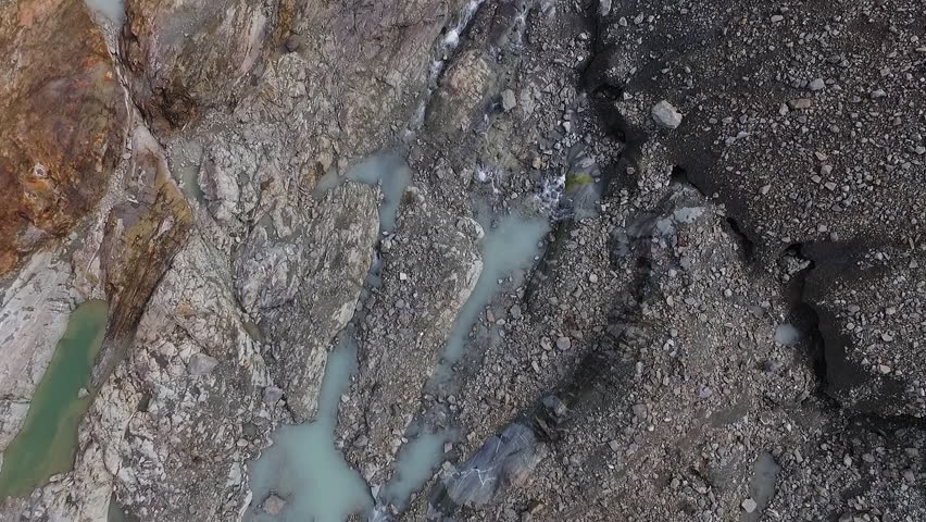 Alpine landscape. Aerial view, descending towards the rocky mountain turquoise water ponds and streams of melting Glacier Vinciguerra in Ushuaia, Tierra del Fuego.