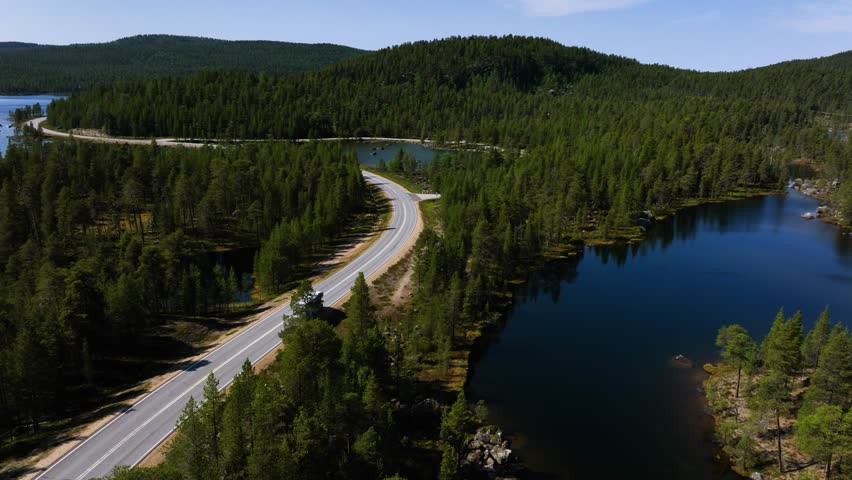 Aerial view following a camper driving polar road, summer day in Inari, Finland