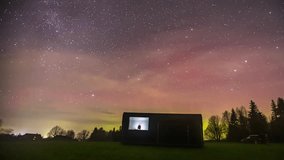 Time-lapse of the stars in the sky. milky way moving over trees in the forest with a little hut. Night and day time lapse shot of the milky way on the earth. Night sky stars milky way on trees