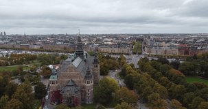 It is an aerial view of the city of Stockholm, Sweden. You can see on the island of Djurgården the Nordic museum and part of the gardens with fluffy trees