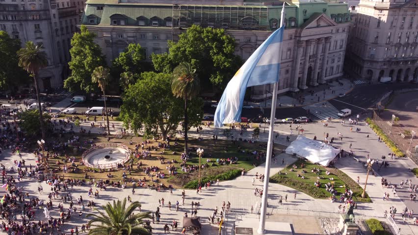 Drone flying around Argentinian flag waving in Plaza de Mayo during march LGBT event pride parade in Buenos Aires city. Aerial orbiting Royalty-Free Stock Footage #1100009719