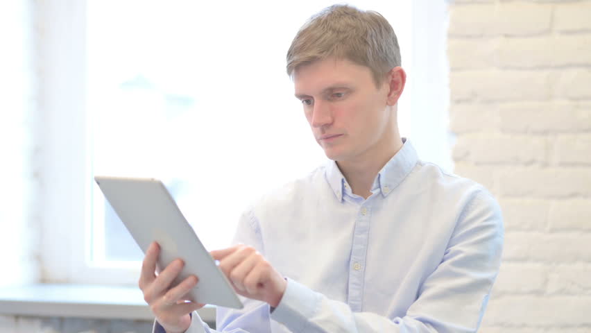 Young Businessman Celebrating Success on Tablet
