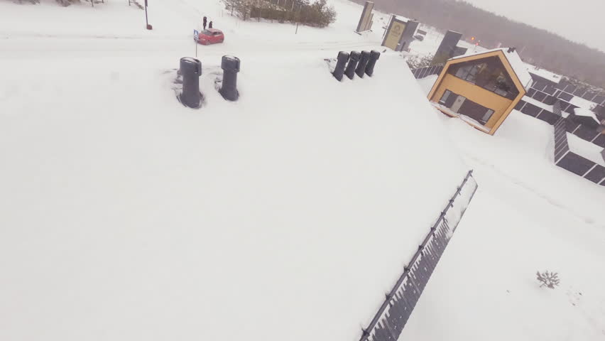 Massive cottage with roof covered with big layer of snow in residential complex. Residential area with luxury villas in frosty winter