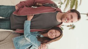 VERTICAL VIDEO: Young happy couple walking hugging along the promenade