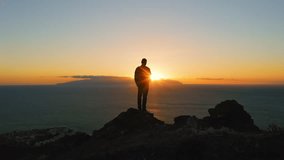 Man standing on top of rock with epic mountain viewpoint colorful sunset light and endless ocean horizon. Drone aerial landscape. - Powered by Shutterstock - Get 15% off with code: PIKWIZARD15