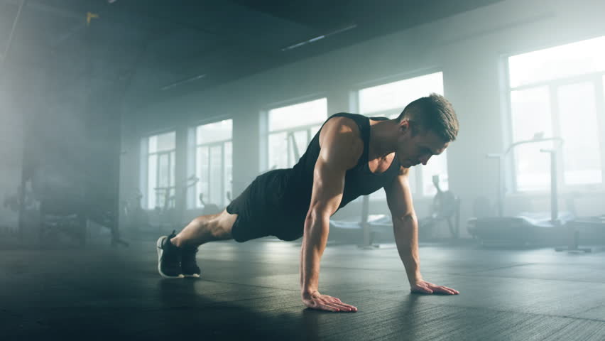 Close-up view of caucasian sportsman in his 30s performing push-ups in modern gym studio. Portrait of active athlete doing set of exercises for arms and back strength. High quality 4k footage Royalty-Free Stock Footage #1100018993