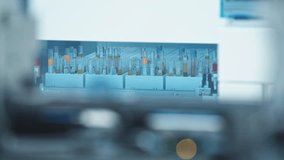 Long shot of test tubes moving around behind the glass in an automated lab in the background. Blurred foreground. Lab concept. High quality 4k footage