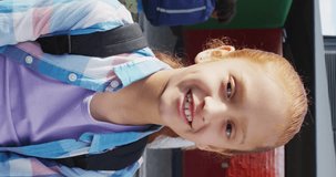 Vertical video of portrait of happy caucasian schoolgirl in school. Education, inclusivity, school and learning concept.