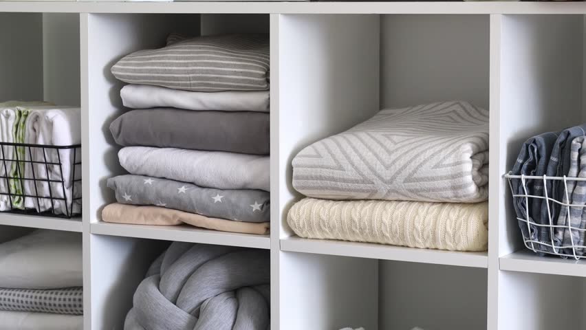 A woman housewife puts bed linen and towels in a beautiful closet. The concept of space organization and storage. Royalty-Free Stock Footage #1100021751