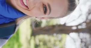 Vertical video of portrait of happy caucasian woman in park, slow motion. Nature, hiking and park concept.