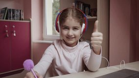 Distance Learning Schoolgirl Studying Online Using Laptop Making Thumbs up. School Student in Headphones Approved Distance Learning Showing Thumbs up. Caucasian Girl Wear Headphones Learn Online Class - Powered by Shutterstock - Get 15% off with code: PIKWIZARD15