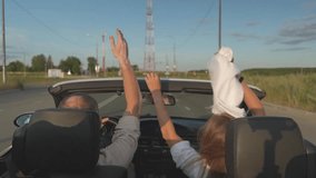 joyful people drive a convertible and wave their hands. a woman holding a white scarf in her hand. FullHD high-quality video recording. slow motion video