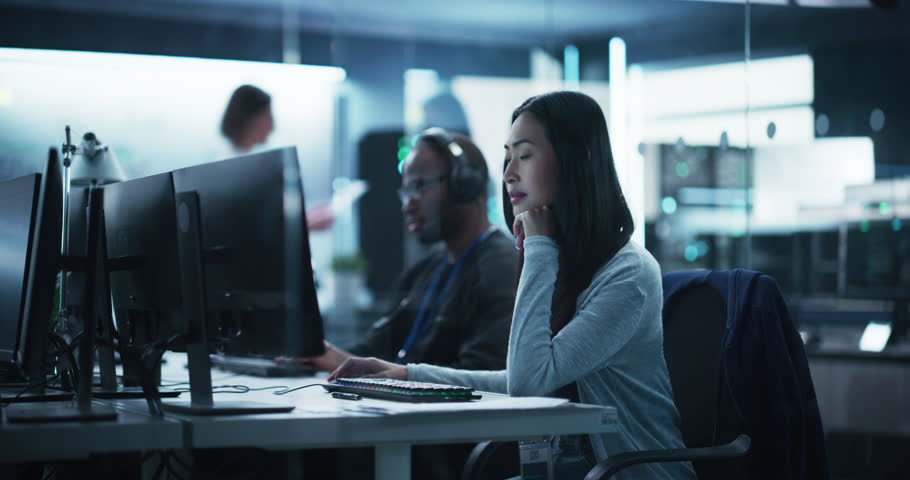 Beautiful Young Asian Female Specialist Working on Computer Together with Professional Colleagues. Data Protection Center with Server Facility, Storage Hardware and Corporate Science Atmosphere | Shutterstock HD Video #1100036341