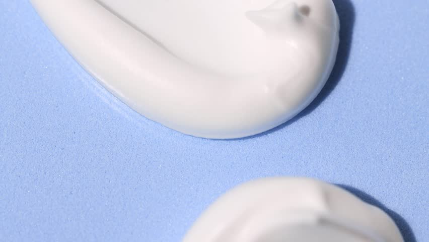 White cosmetic texture, foam, face cream close-up on a blue background. Samples of natural cosmetics, top view. Royalty-Free Stock Footage #1100036715