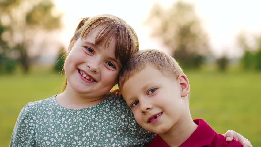 Sister brother smiling while looking camera sunset. friendship portrait boy girl. first graders kid sunset. childish smile. childhood dream child. teamwork. friends hugging camera. happy family sunset | Shutterstock HD Video #1100037191