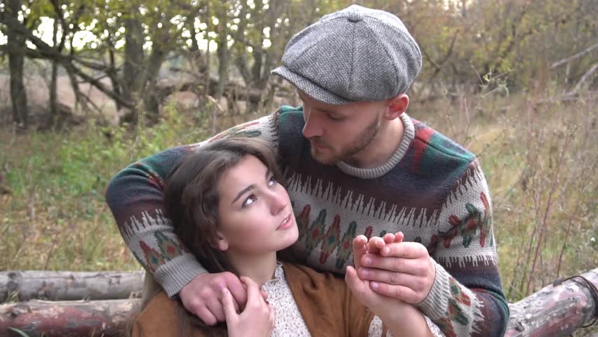 Slow Motion Couple in love sits on a log. Sunset. Forest.