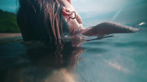 an Asian woman floating on the seawater while swimming on the beach on an island during the day Video Stok