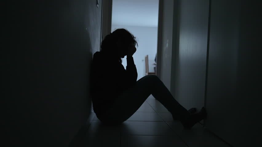 Depressed woman sitting on floor. Sad unhappy person holding her forehead suffering from mental illness