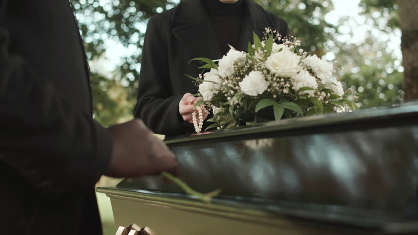 Cropped shot of unrecognizable Black man hand putting one white rose on black coffin lid at outdoor funeral ceremony Royalty-Free Stock Footage #1100042547