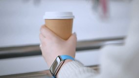 Close up of hands of unrecognizable business woman drinks coffee sitting on a sofa while using a smartphone. Working woman sends text messages from cell phone, working online. 4k video.
