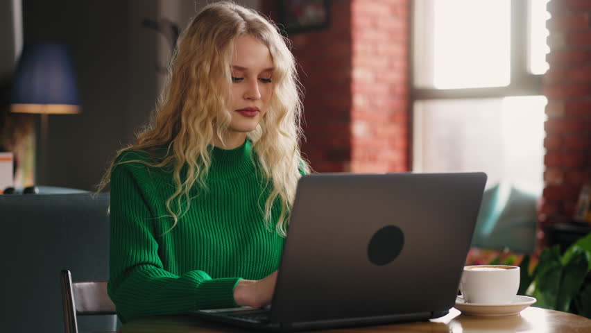 Remote Connectivity: Blonde Woman Efficiently Typing a Message on Laptop Keyboard in a Cozy Cafe During the Day, Chatting Online | Shutterstock HD Video #1100046133