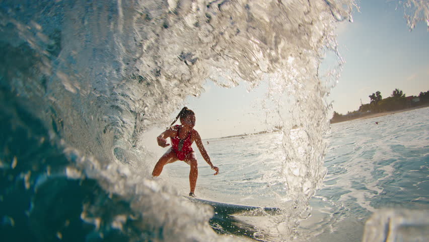 Girl surfer rides the wave. Woman in red suit surfs the ocean wave in the Maldives