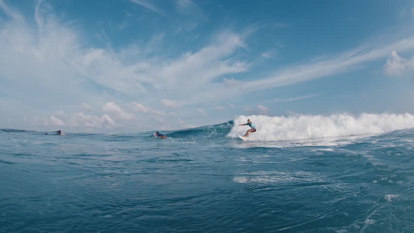 Happy surfer rides and smiles. Young man surfs the ocean wave in the Maldives and smiles