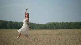 a girl with red hair in a white dress dances in a field. slow motion video. High quality Full HD video recording