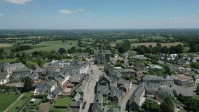Saint Corneille and Saint Cyprien church in La Baconnière municipality and countryside in background, Mayenne in France. Aerial forward tilt down and sky for copy space
