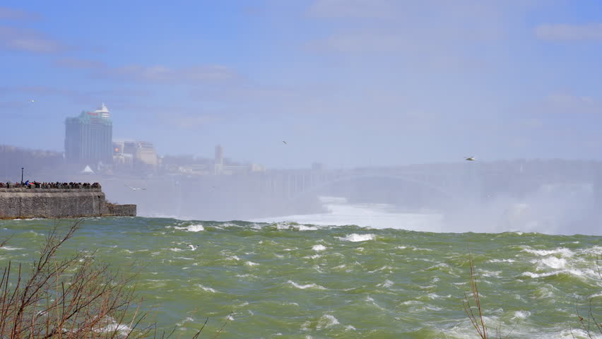 Establishing shot of majestic Niagara Falls with snow and icy at mountain background in Toronto, Canada, North America. Day time on March 2022. ProRes 422 HQ.