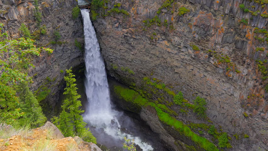 Establishing shot of majestic mountain waterfall with mountain background in Vancouver, Canada, North America. Day time on July 2022. Still camera view. ProRes 422 HQ.