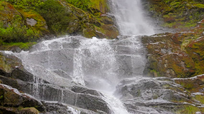 Establishing shot of majestic mountain waterfall with mountain background in Vancouver, Canada, North America. Day time on July 2022. Still camera view. ProRes 422 HQ.