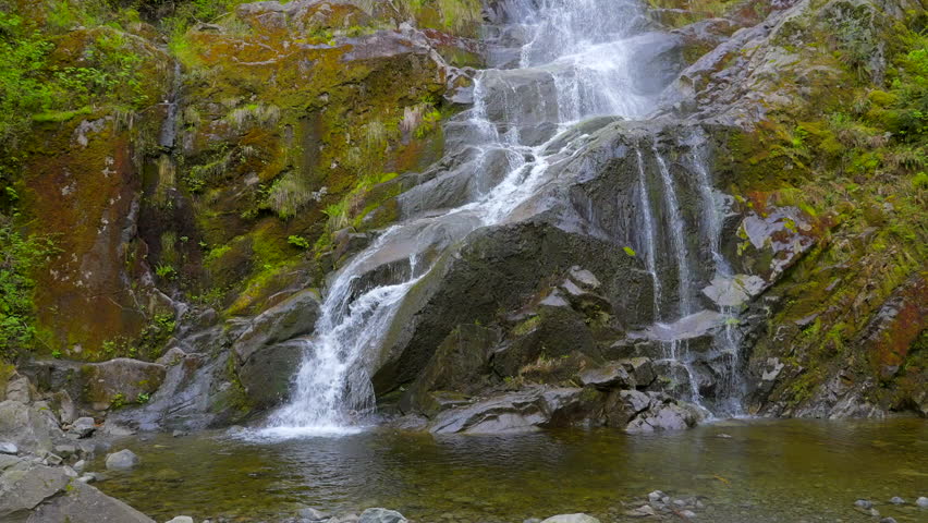 Establishing shot of majestic mountain waterfall with mountain background in Vancouver, Canada, North America. Day time on July 2022. Still camera view. ProRes 422 HQ. | Shutterstock HD Video #1100048409