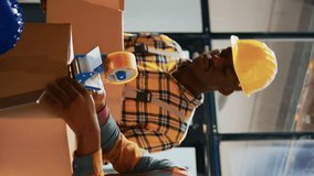 Vertical video: Storage room workers packing boxes with tools in depot, using laptop to plan logistics. Men and woman working with merchandise to ship in containers and carton packages, shelving - Powered by Shutterstock - Get 15% off with code: PIKWIZARD15