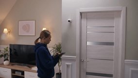 Caucasian woman completes installation of security camera. Woman sets up CCTV camera at home using digital tablet computer and application. Monitoring system, safety and privacy concept. Zoom in shot. - Powered by Shutterstock - Get 15% off with code: PIKWIZARD15