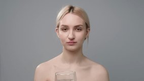Close up of young beautiful woman drinking lemon detox water. Healthy eating, portrait of a beautiful laughing woman. Slow video.