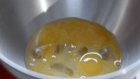 Adding sugar to raw eggs in a silver kitchen stand mixer, for whipping the eggs. Slow motion video, Selective focus.