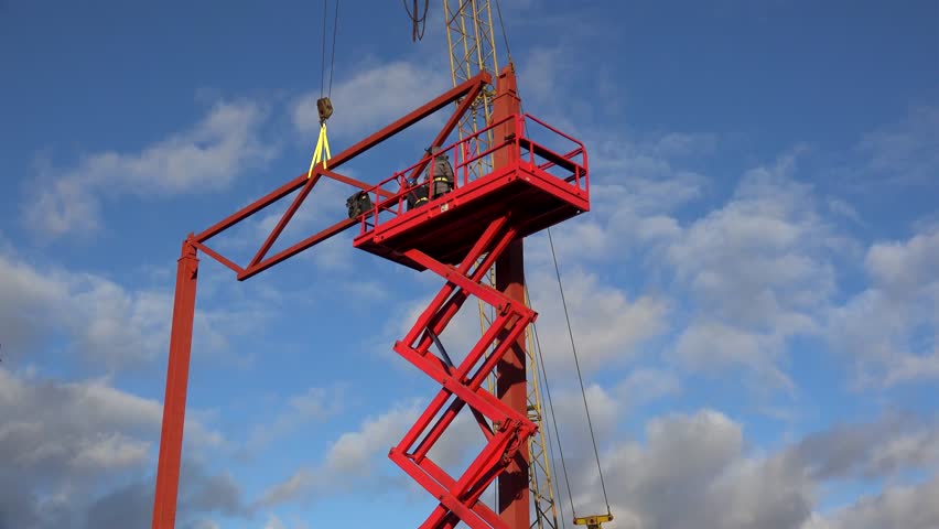 Workers are lifting on the Aerial Work Platform (Scissor lift) to secure the beam frame. Royalty-Free Stock Footage #1100056929