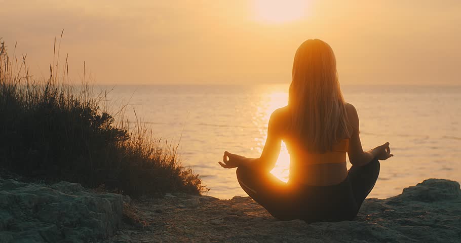 Young women are doing yoga in summer sunset with sea background. Warm-up, healthy life, relaxing and outdoor exercise. Health care, authenticity, sense of balance and calmness. | Shutterstock HD Video #1100057793