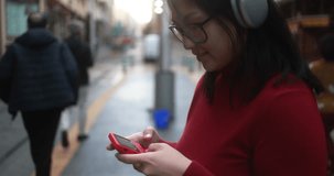 Young asian woman gaming with vintage device and listening music playlist with wireless headphones - City lifestyle concept