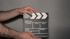 movie clapper board. hands using a clapperboard on grey background. film or television production. concept of cinematography or movie and film crew. video and audio sync tool. movie filming device